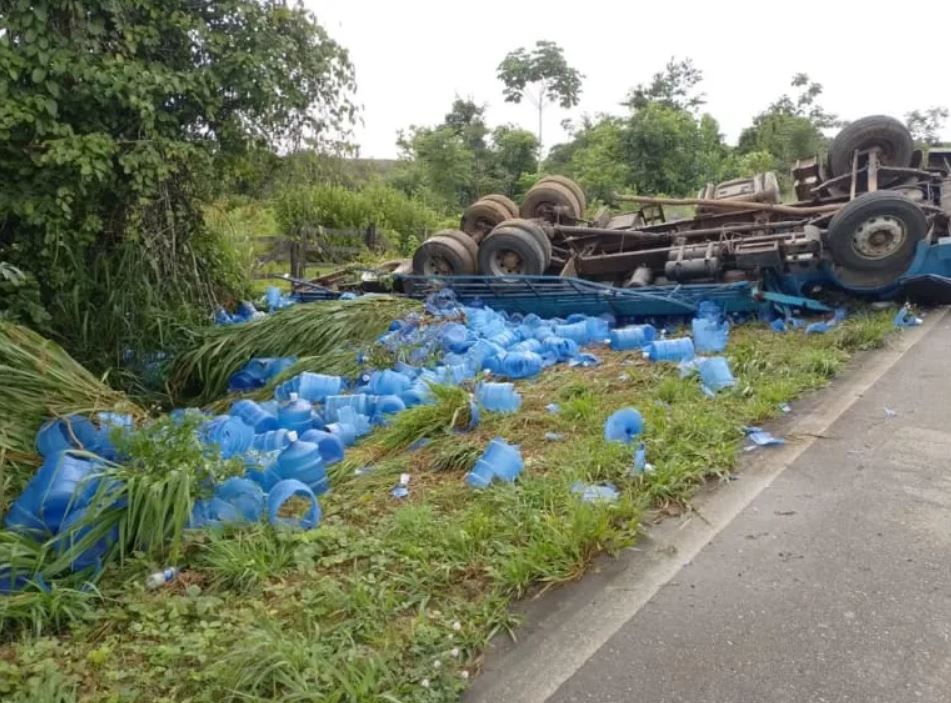 Motorista é resgatado após caminhão com galões de água capotar na BR-364